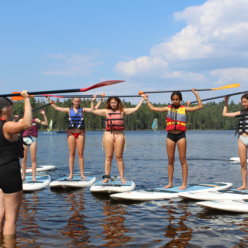 campers stand up paddle boarding